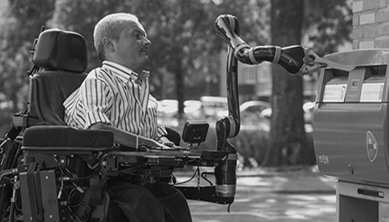 man on a power wheelchair mounted with a Kinova robot